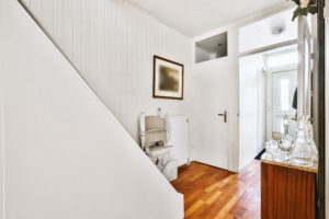 Small house hallway with parquet floor and white walls equipped with stairs chair lift